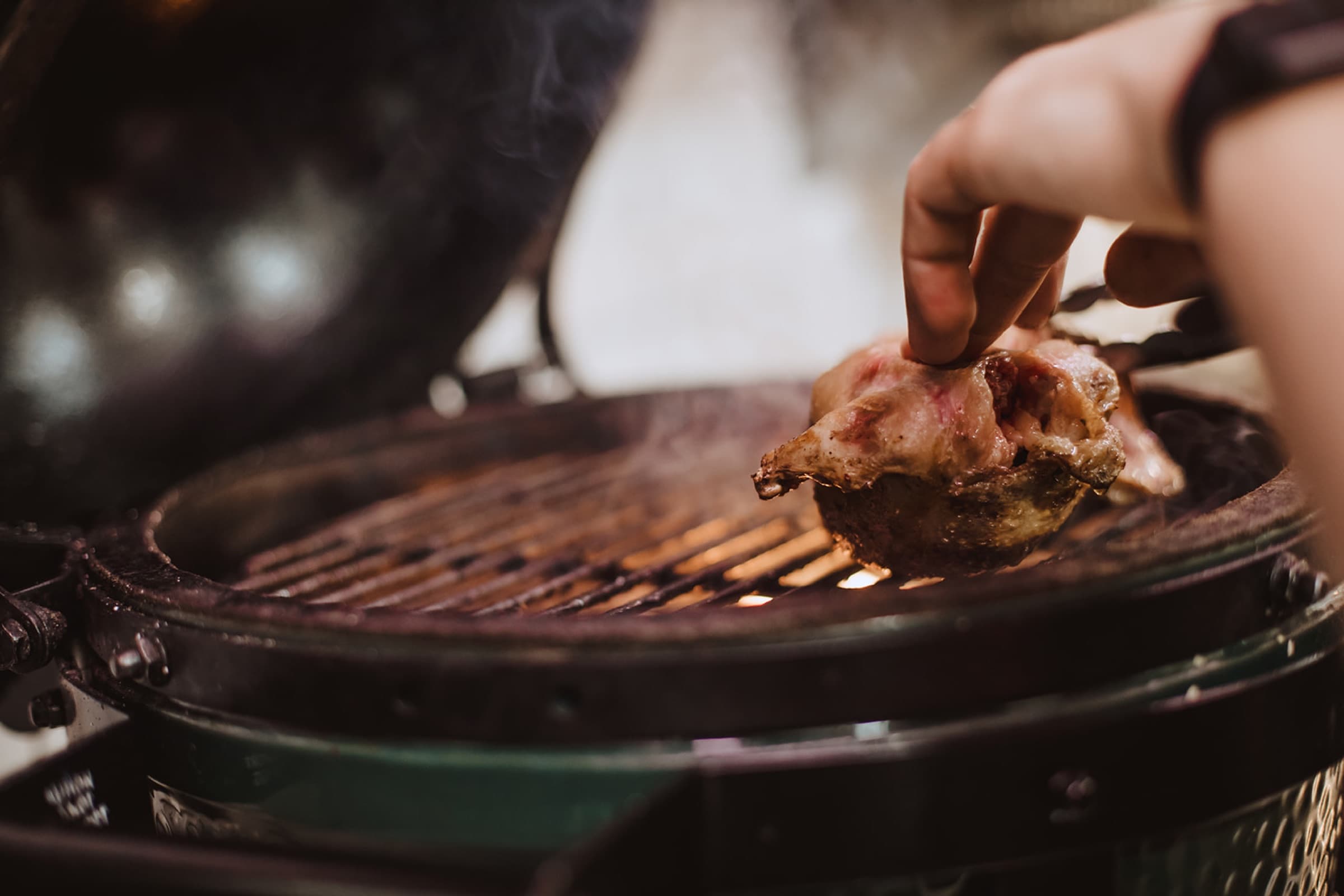 La braise du grill, une main dépose une pièce