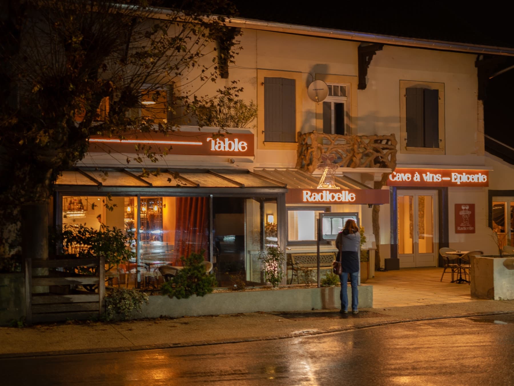La façade, le soir — table, cave à vins, épicerie